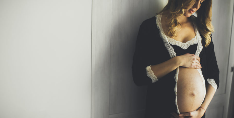 Photo of beautiful pregnant woman wearing lingerie and posing in the room